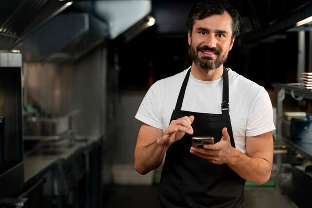 Imagem do dono de um restaurante com um celular na mão